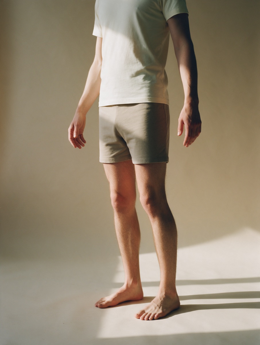 A person in a plain base tee and shorts, ready to try something on